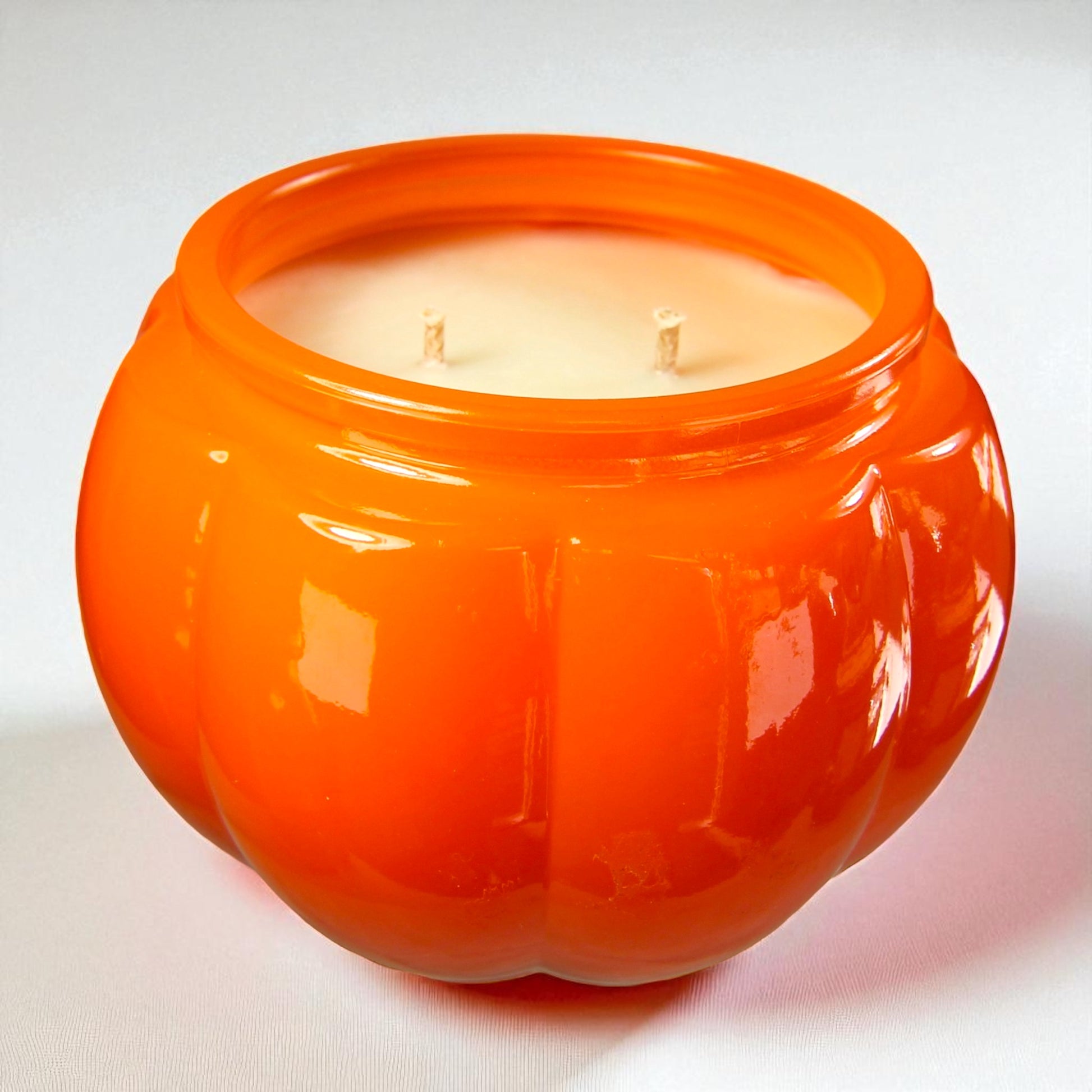 Orange pumpkin-shaped candle with three wicks on a white background